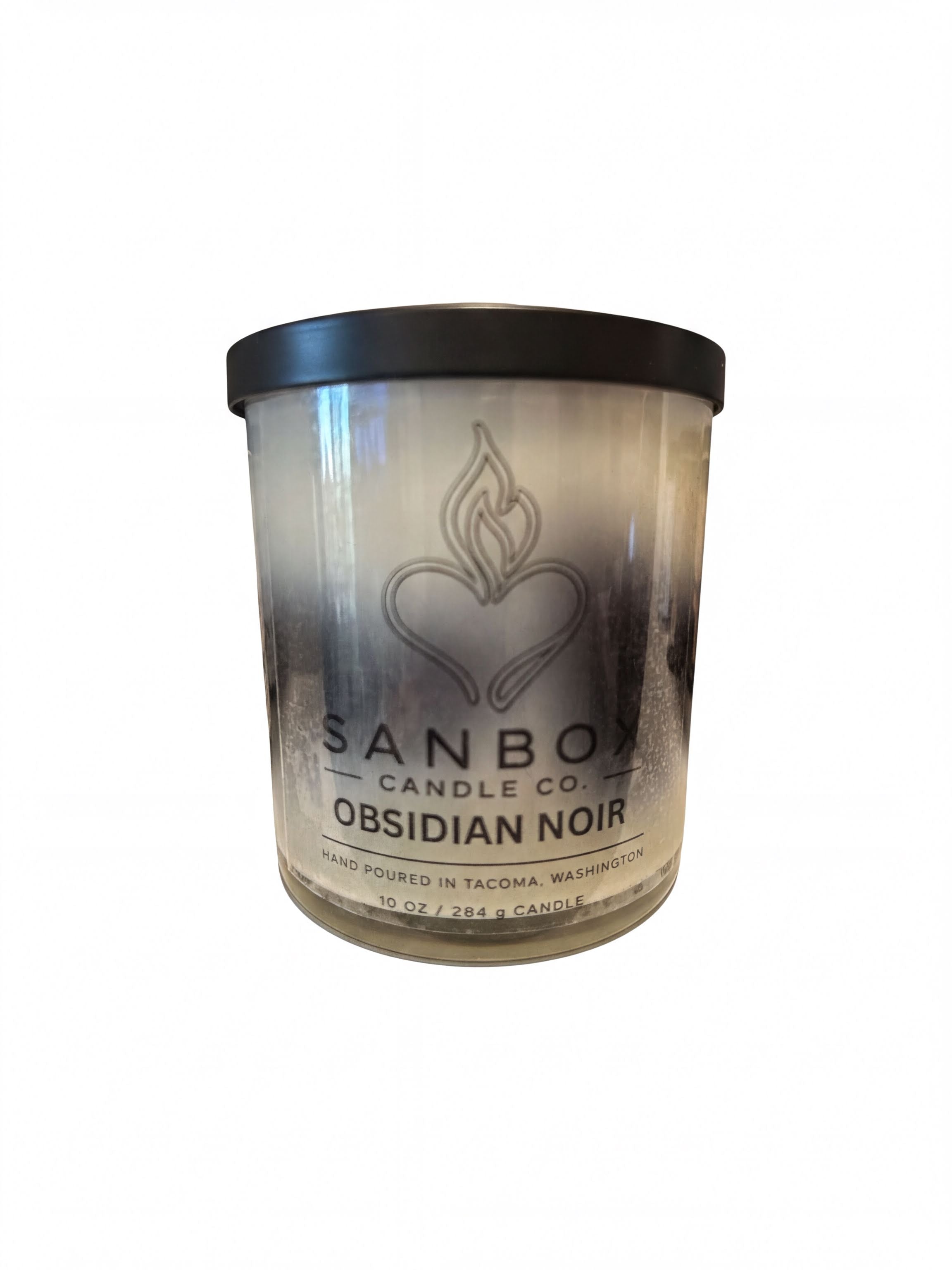 a cylindrical candle in a glass container with a black lid.