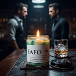 a candle labeled "FAFO" on a table, with a glass of whiskey and a man in a black shirt in the background.