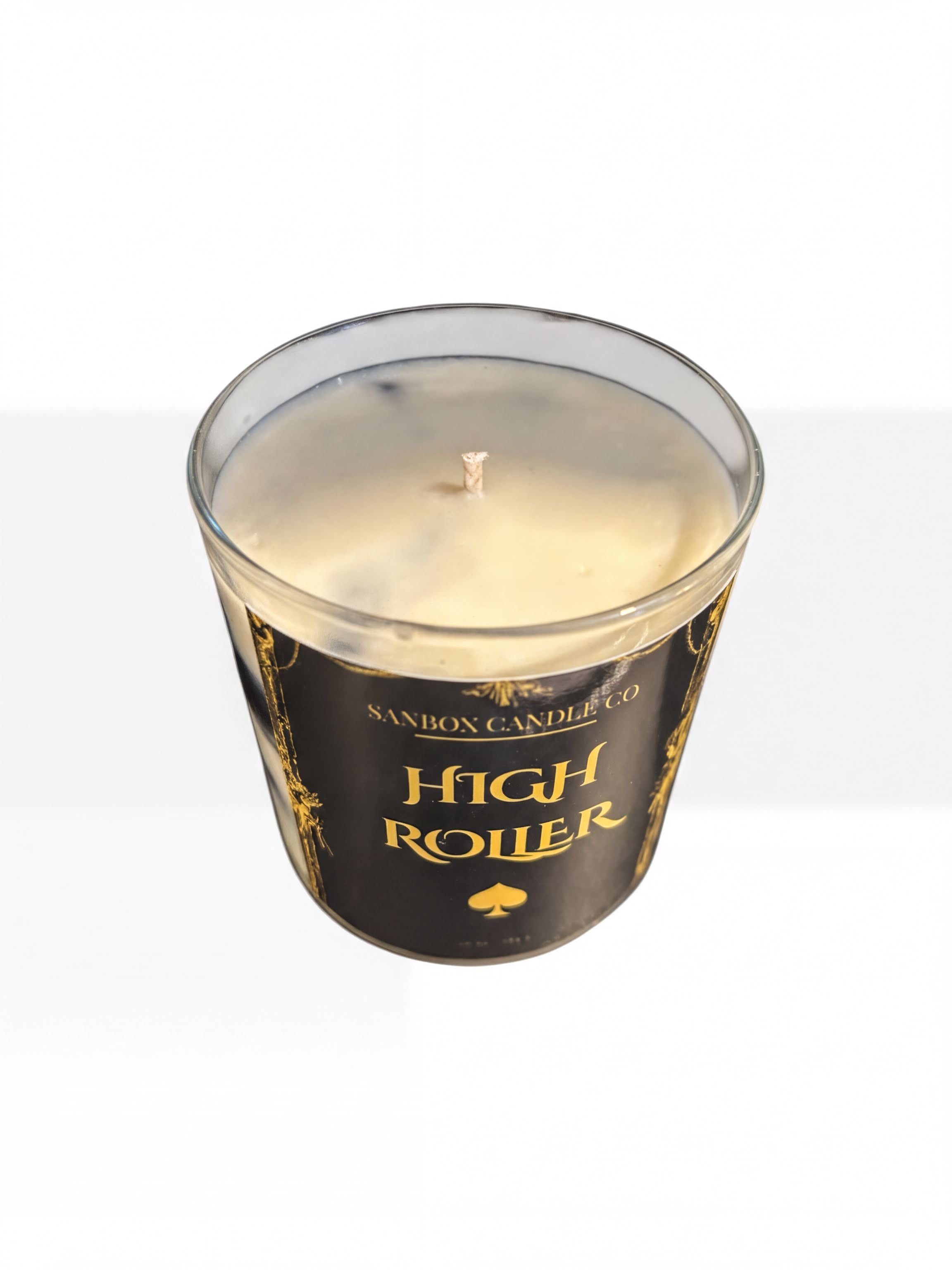 A glass candle holder with a candle inside, labeled "High Roller".