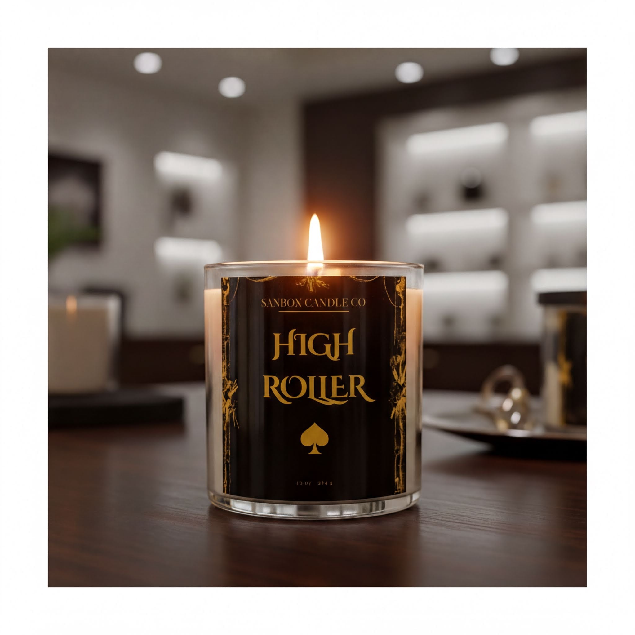 A lit candle labeled "High Roller" sits on a wooden surface, with a blurred background that includes shelves and other items.