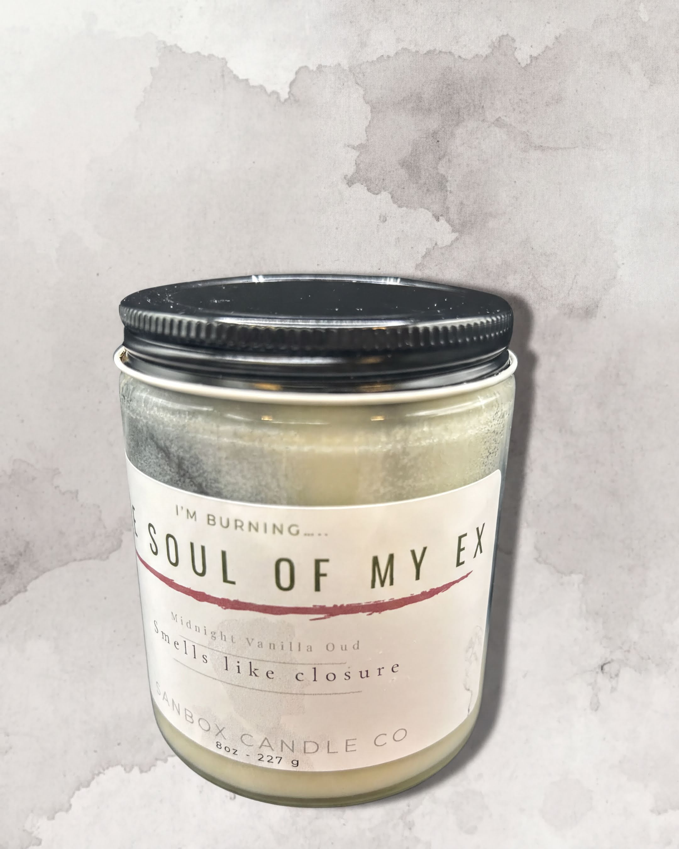 a candle labeled "I'm Burning... Soul of My Ex" in a jar with a black lid.