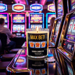 A candle labeled "MAX BET!" sits on a reflective surface in front of a row of slot machines in a casino, with a person visible in the background.