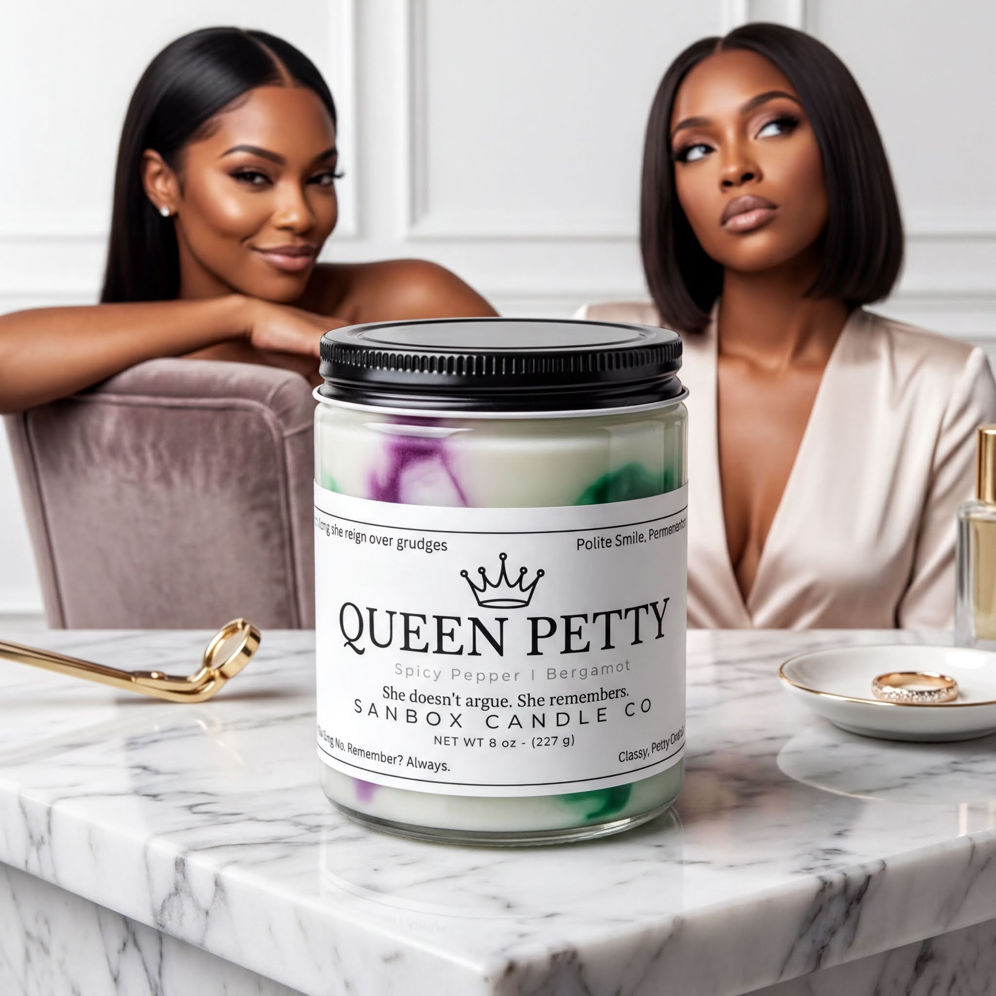 two women sitting on a marble countertop, with a large jar of Queen Petty candle in the foreground.