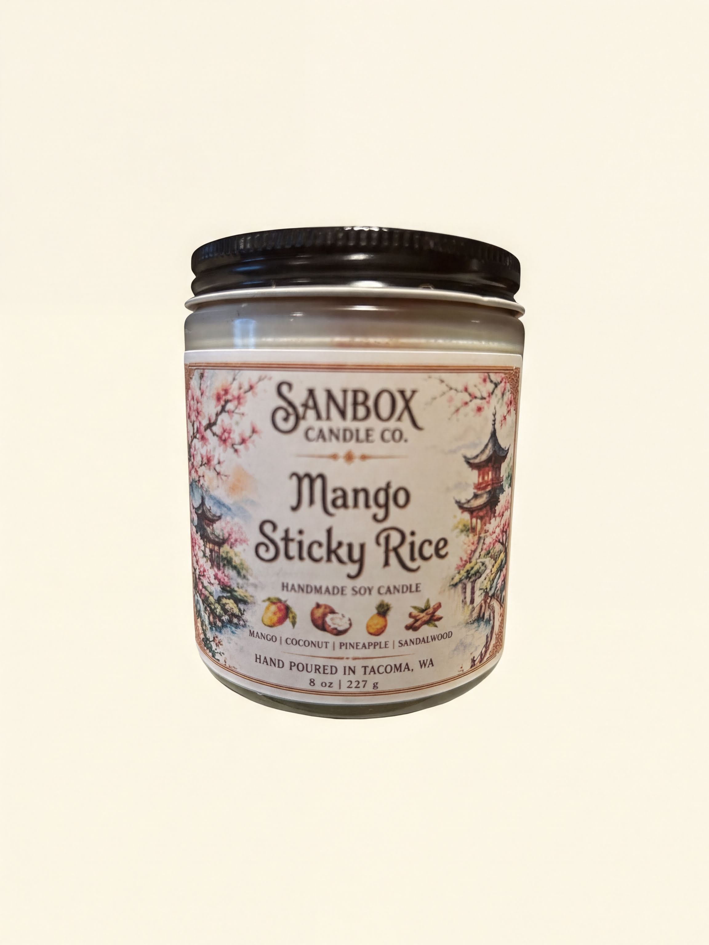 a candle in a jar with a label that reads "Sanbox Candle Co. Mango Sticky Rice Handmade Soy Candle".