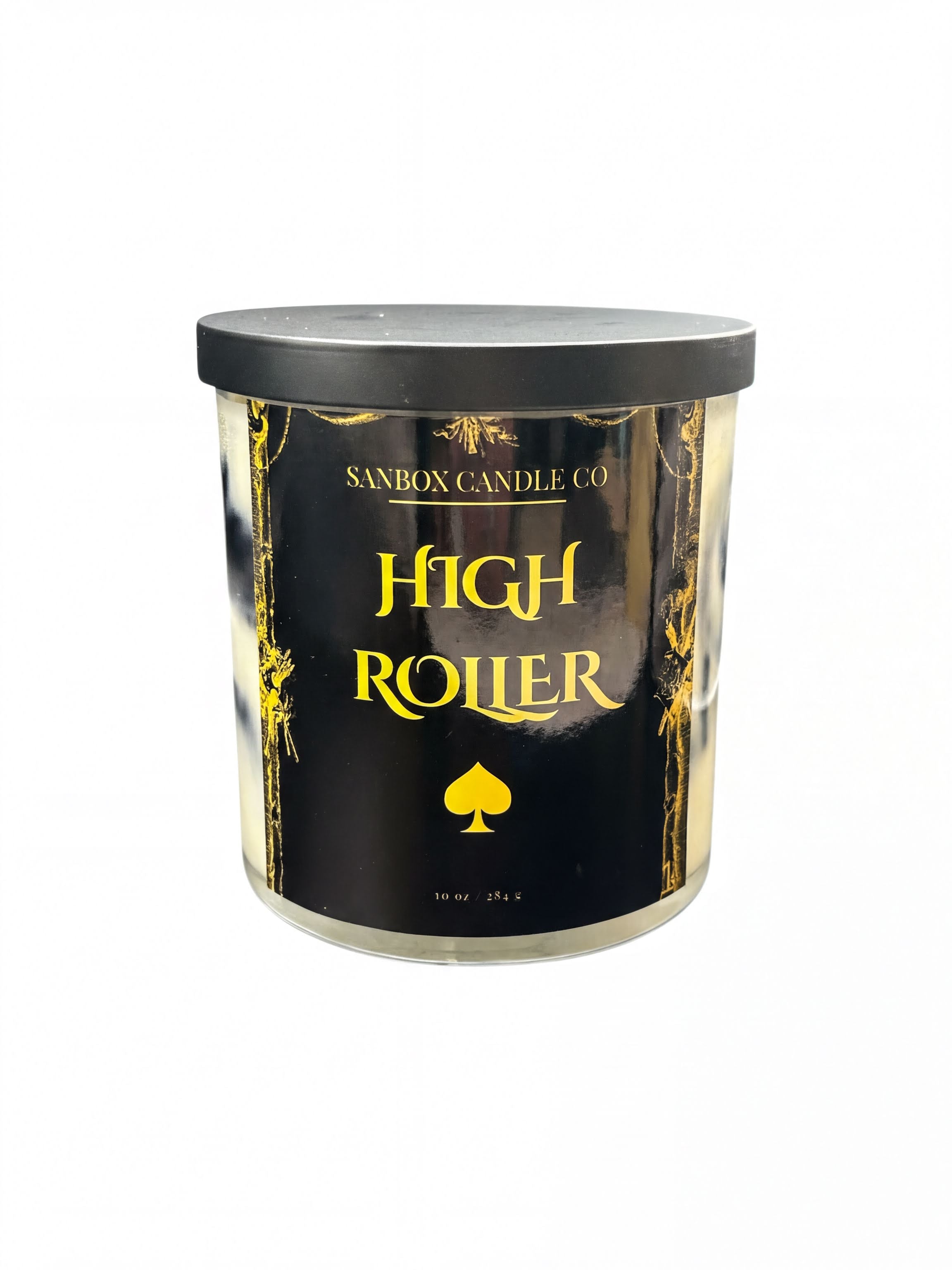 a cylindrical candle labeled "High Roller" in a black and gold color scheme.