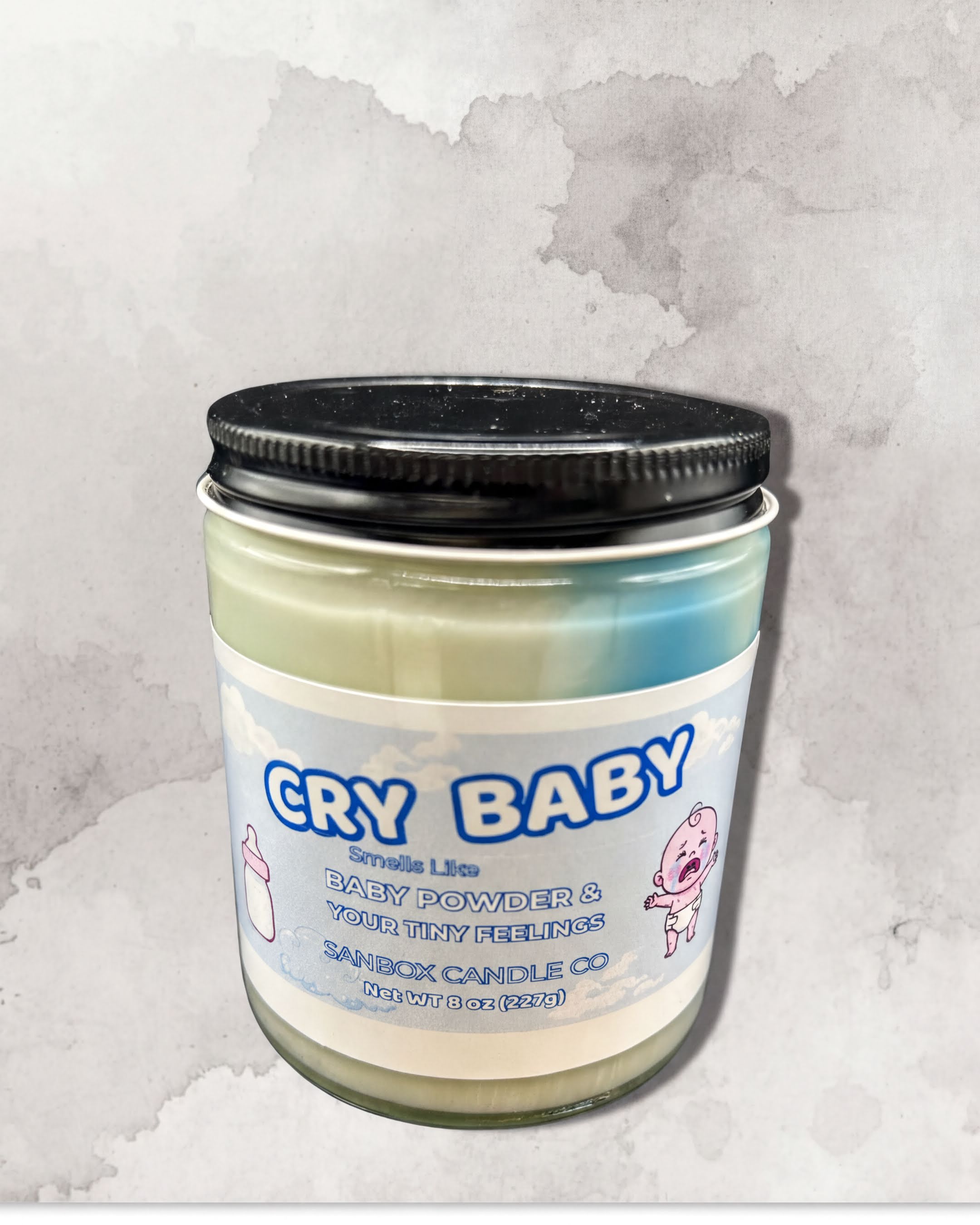 a candle labeled "CRY BABY" with a baby bottle icon and a baby's face.