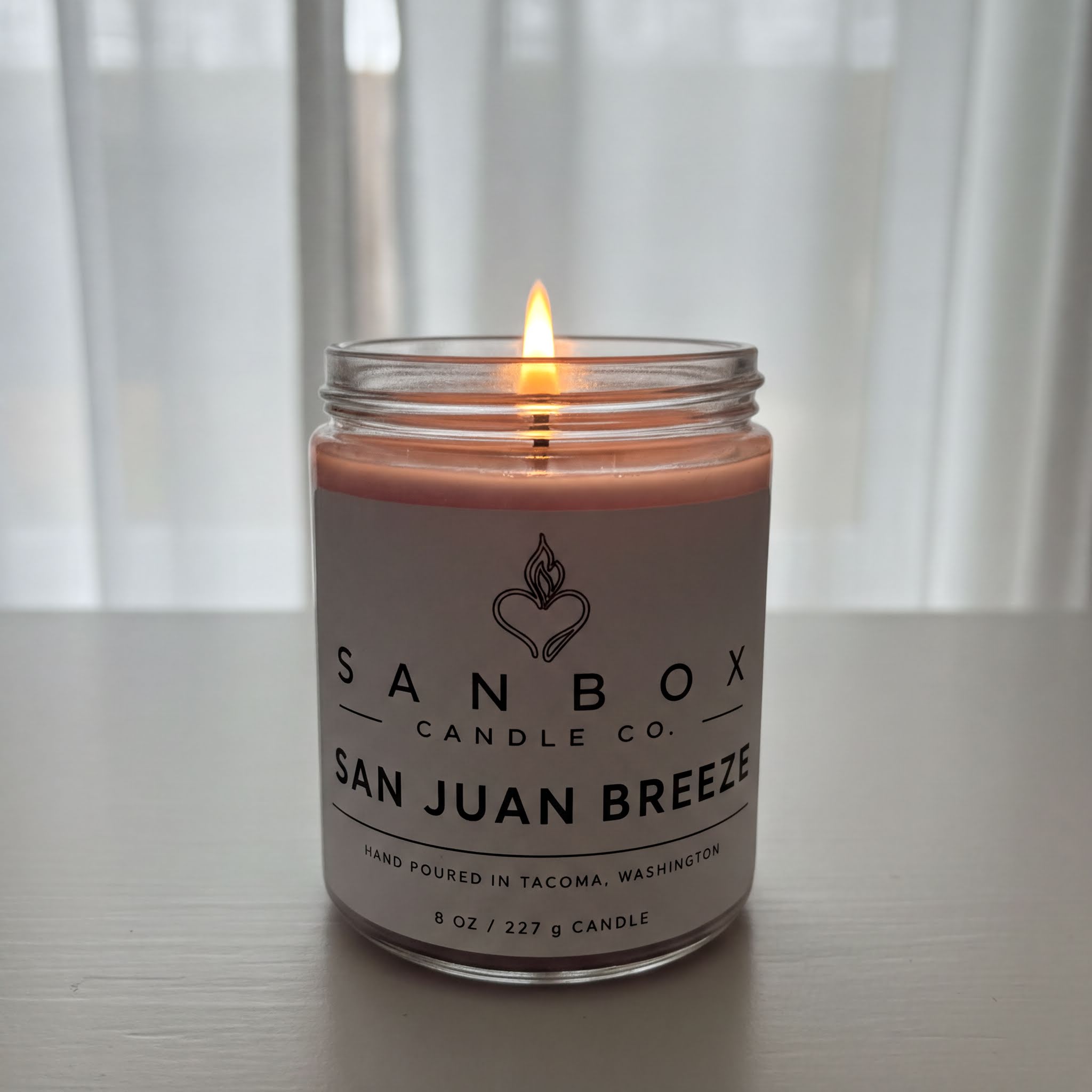 A lit candle in a jar, with a label that reads "SAN BOX CANDLE CO. SAN JUAN BREZE".