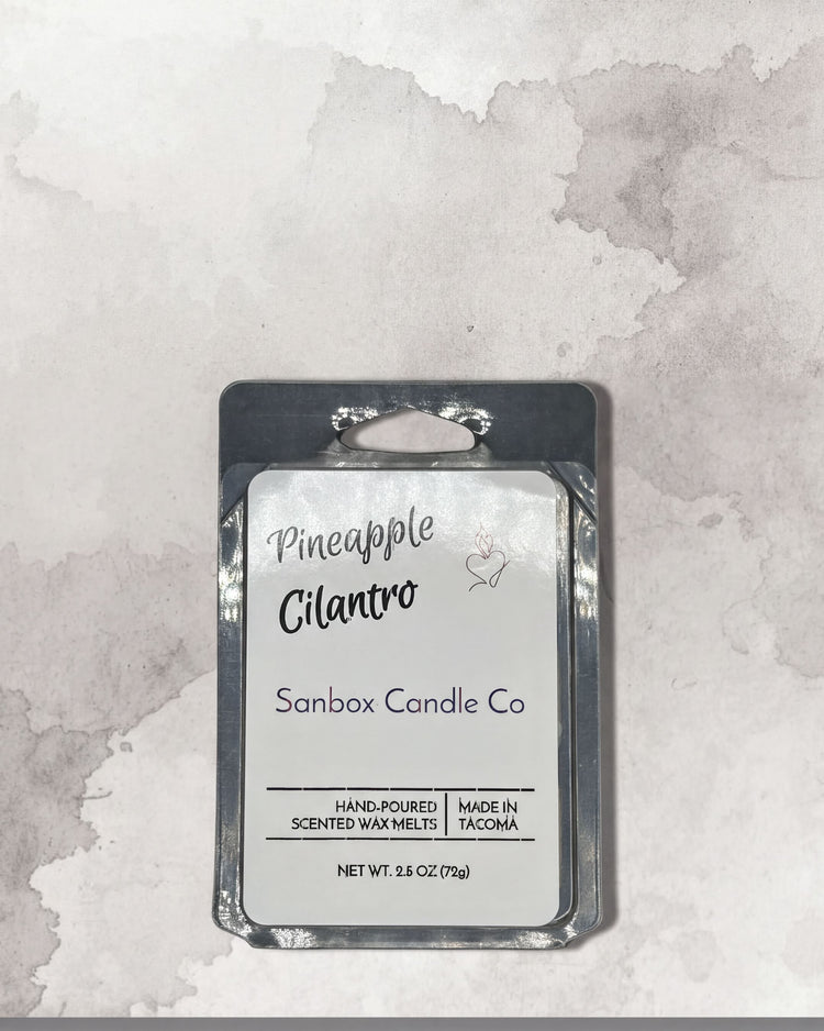 a package of Pineapple Gilante candles from Sanbox Candle Co. The package is placed on a textured gray background.