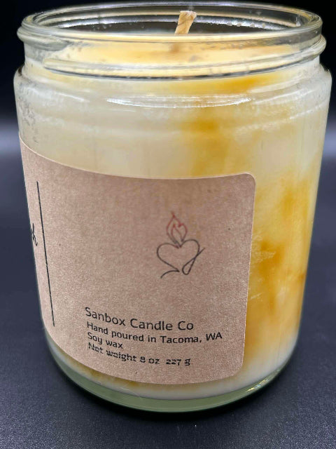 8 ounce Butterscotch Bourbon Candle without lid on a dark background showing side label.