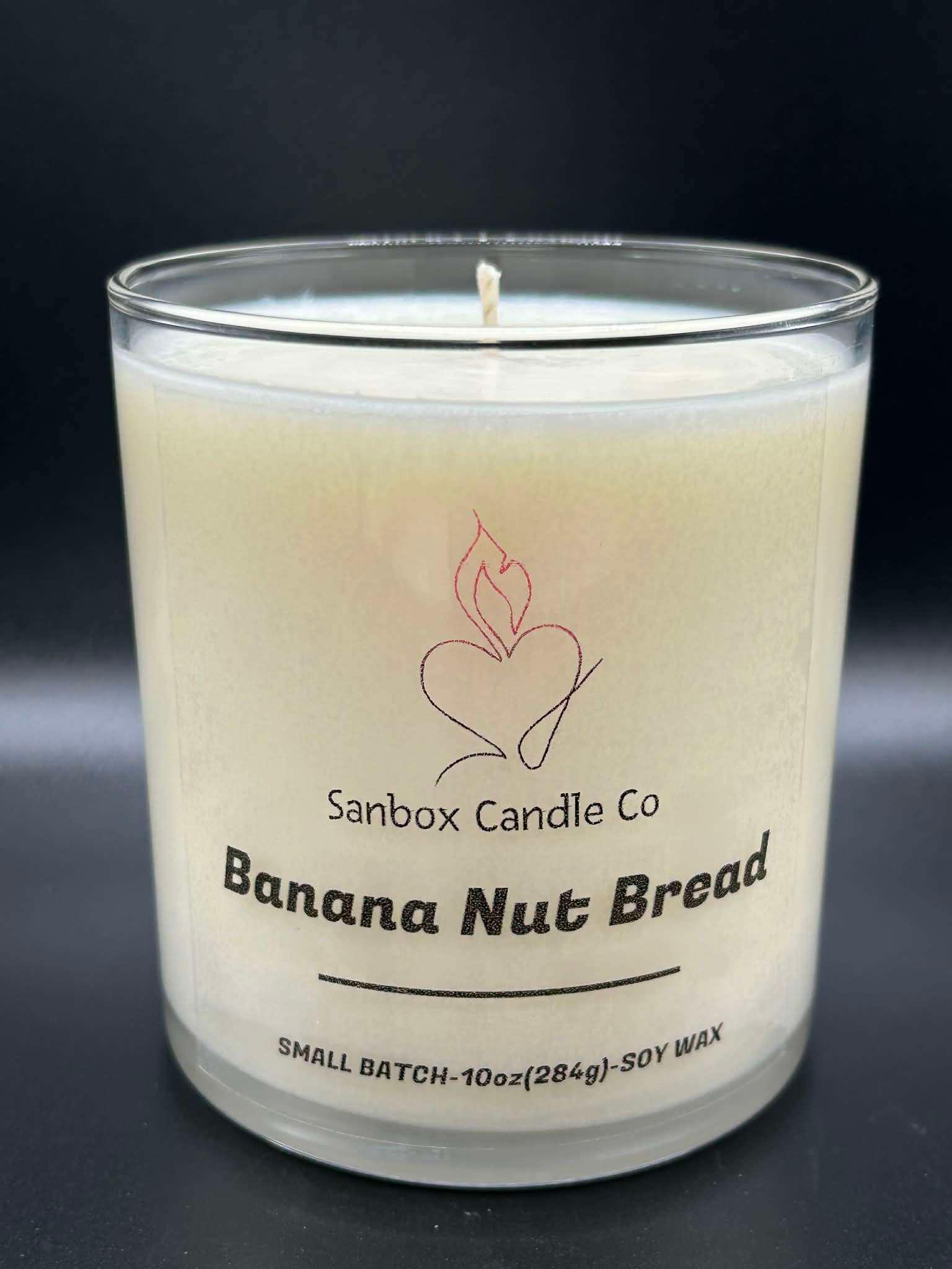 Banana Nut Bread scented soy wax candle in a clear glass jar, 10oz size, on black background.
