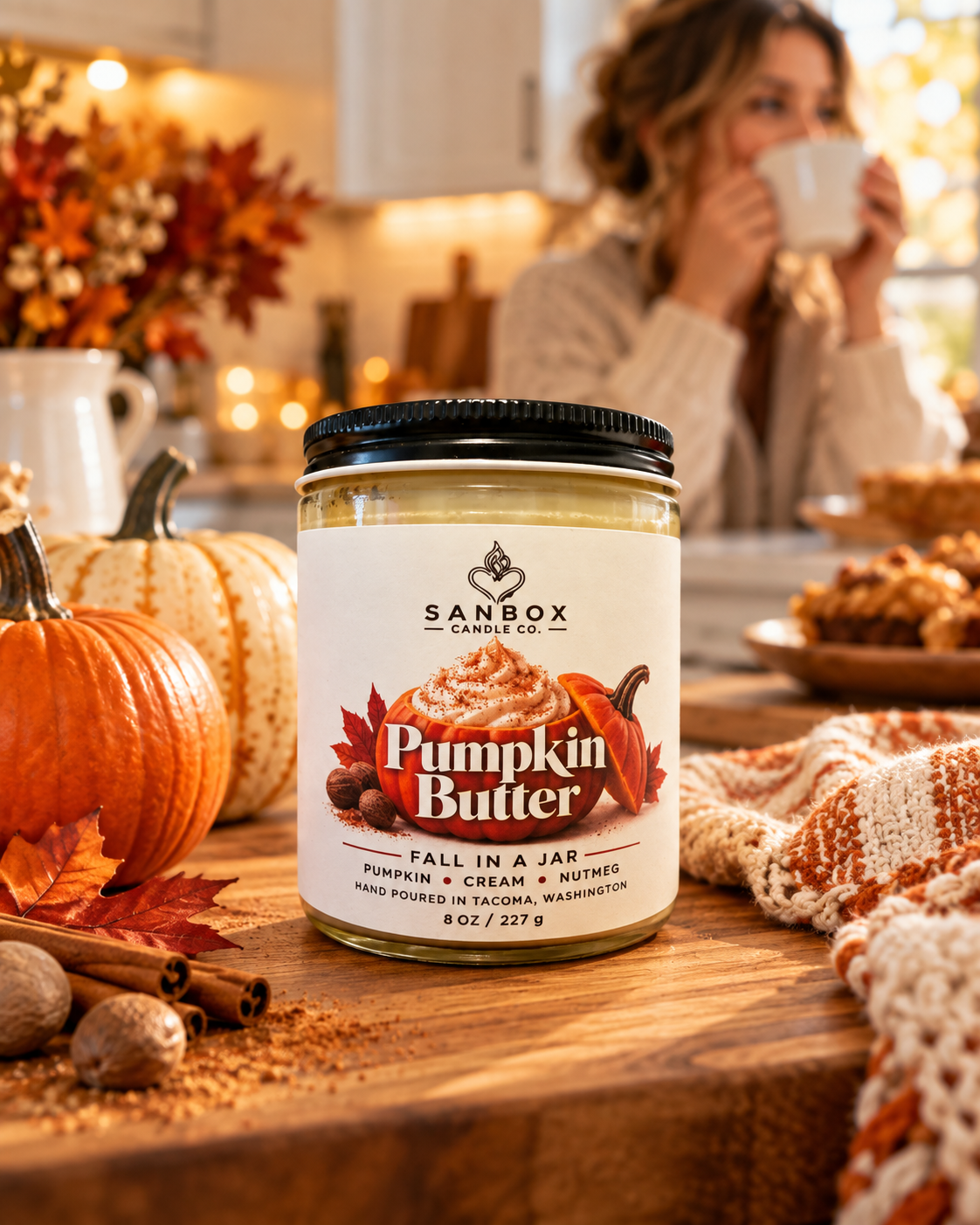 Pumpkin Butter 8 oz hand-poured soy candle in a clear glass jar with black lid and creamy wax, styled with pumpkins, autumn leaves, and Halloween decor in a cozy living room.