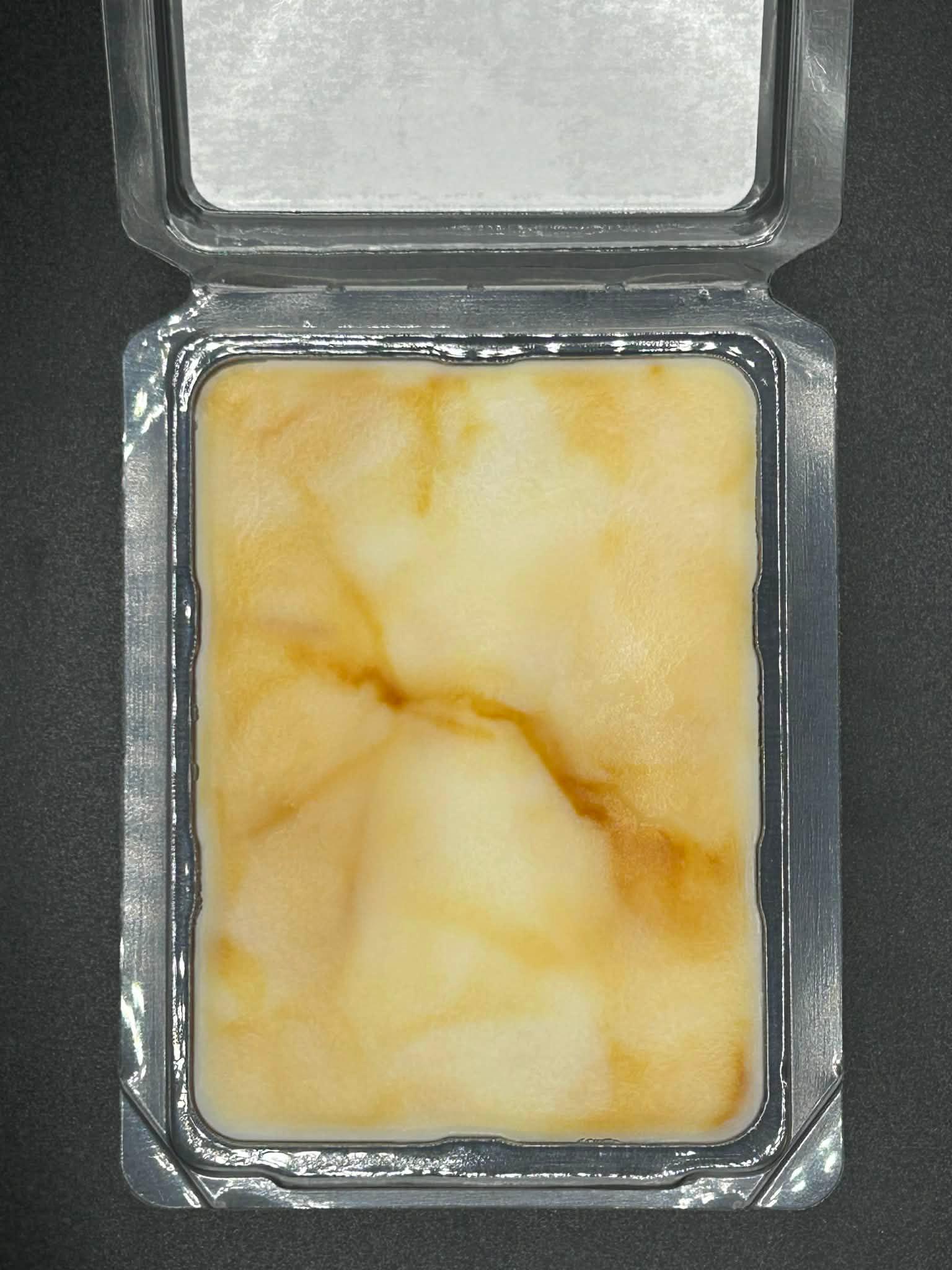 Open clamshell tray with hand-poured scented wax melt, marbled cream and amber hues