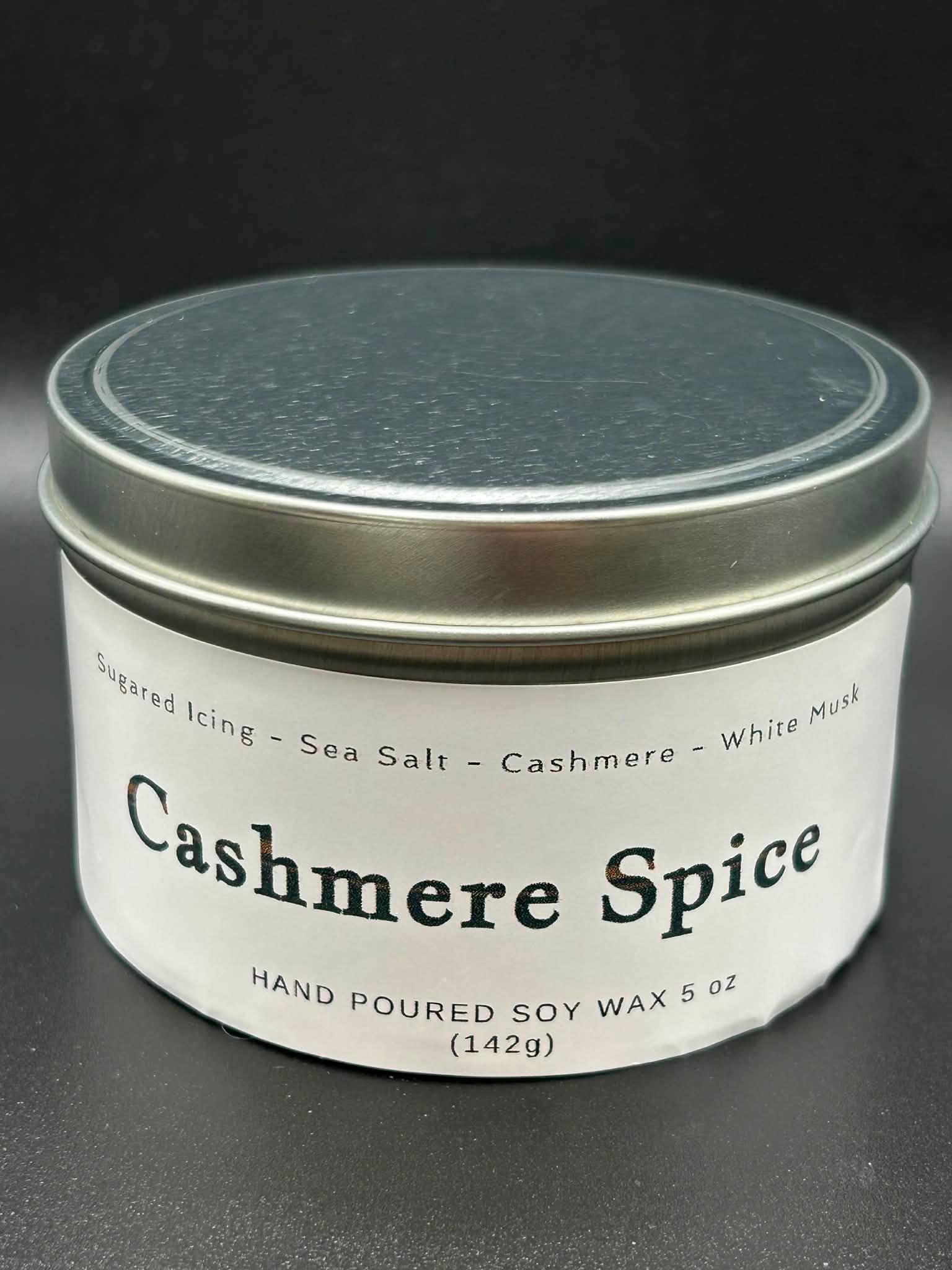 Cashmere Spice hand-poured soy wax candle tin, 5oz, with scent notes of sugared icing, sea salt, cashmere, and white musk, against a black background.