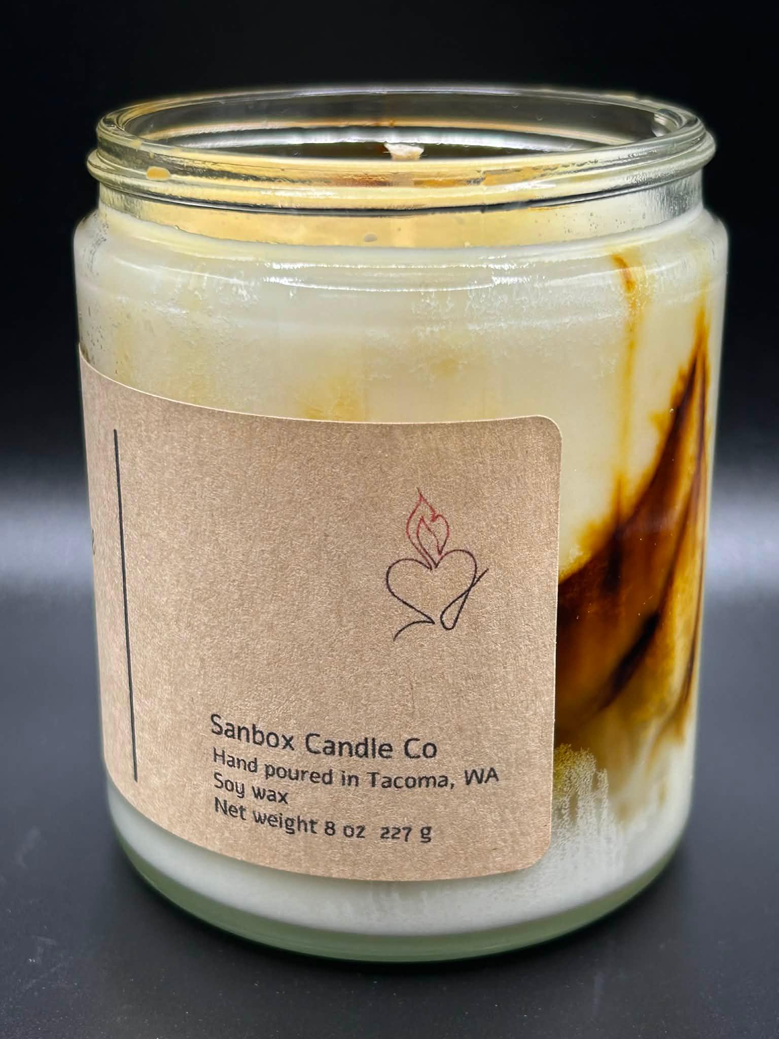 Hand-poured soy wax candle in glass jar with rustic brown label, 8oz size, marbled design.