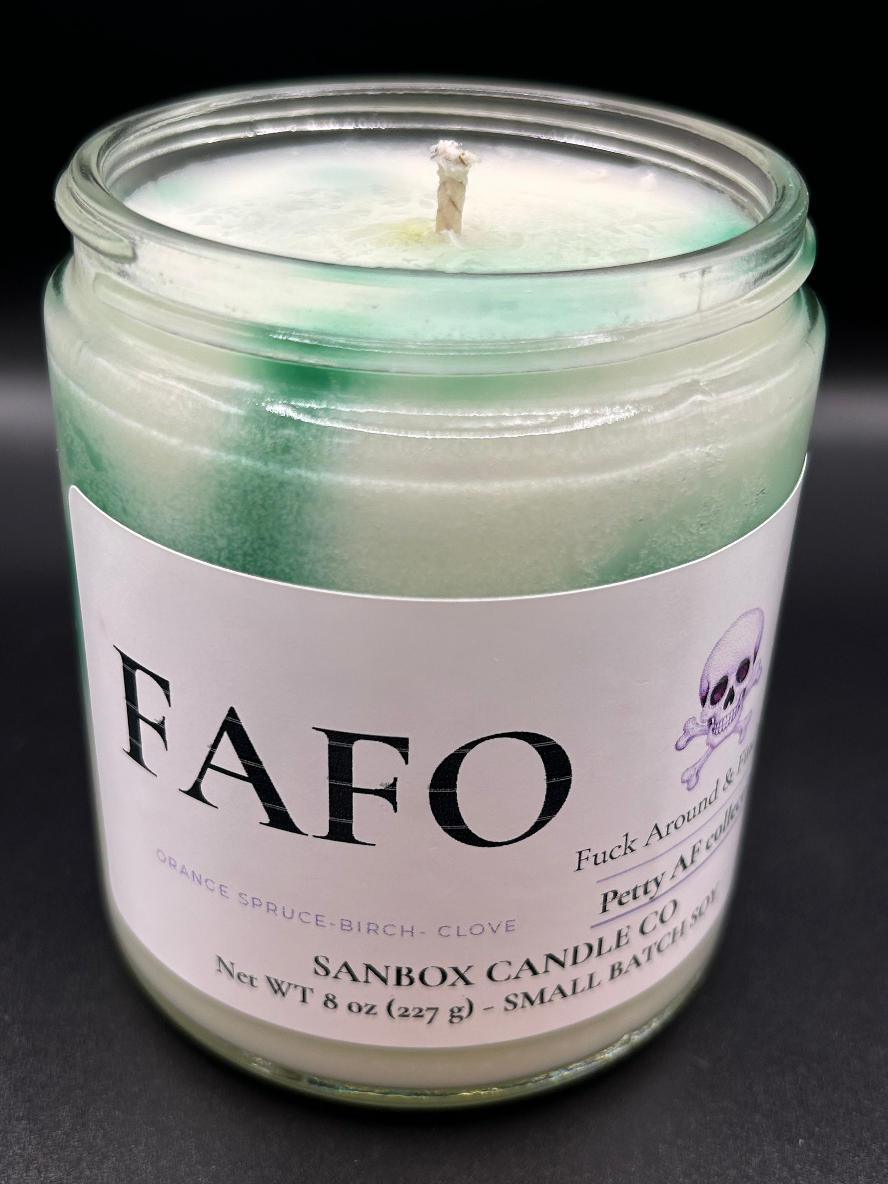 Green and white hand-poured scented candle in glass jar with FAFO label and skull graphic.