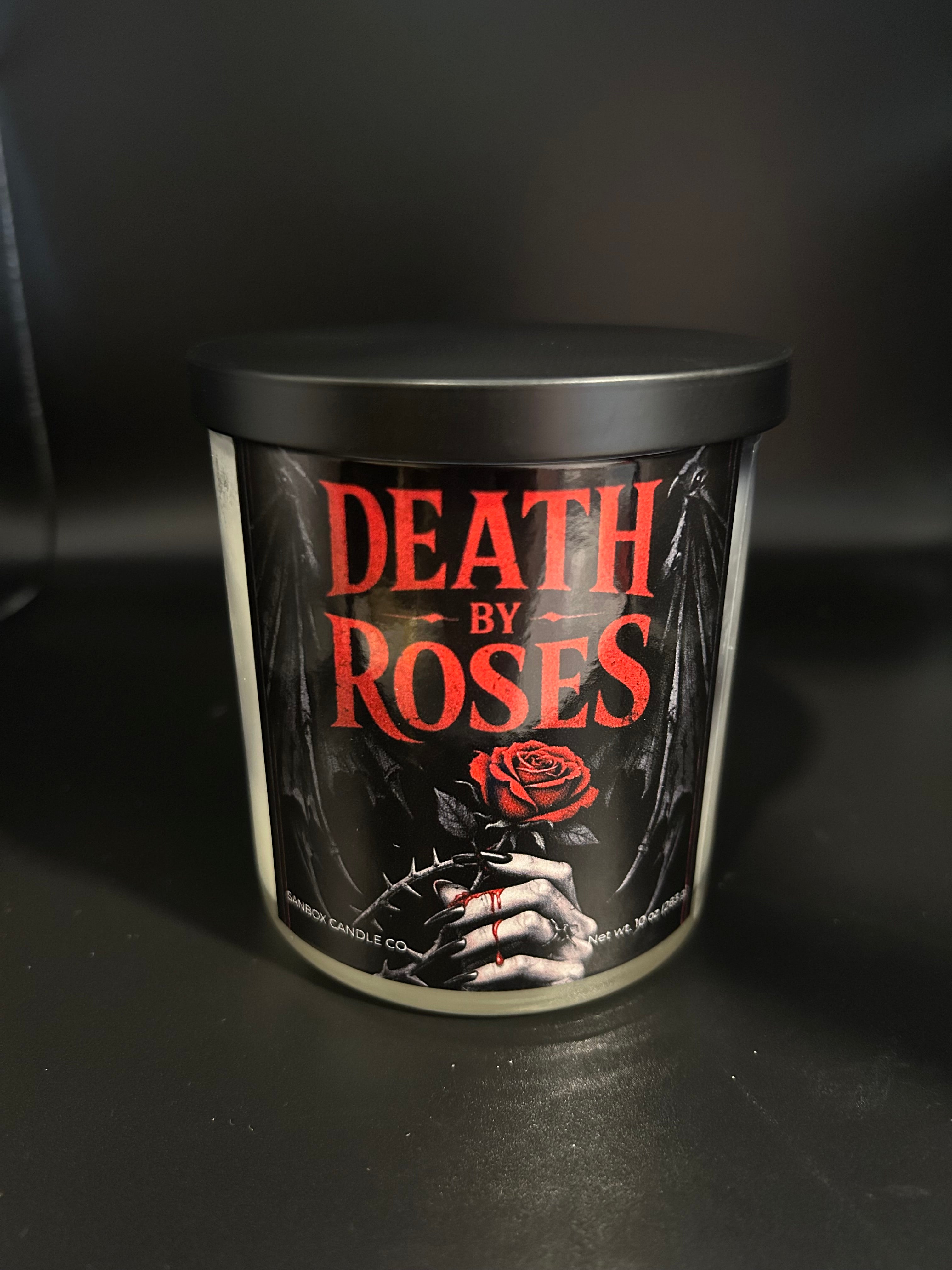 a cylindrical container with a black lid, displaying a label that reads "DEATH BY ROSES" and includes a rose and a hand with a thorny rose.