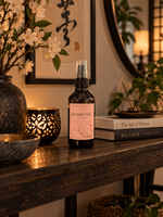 Jasmine Veil jasmine floral room spray in an amber bottle with a blush pink label, styled on a dark wood console beside jasmine blossoms 