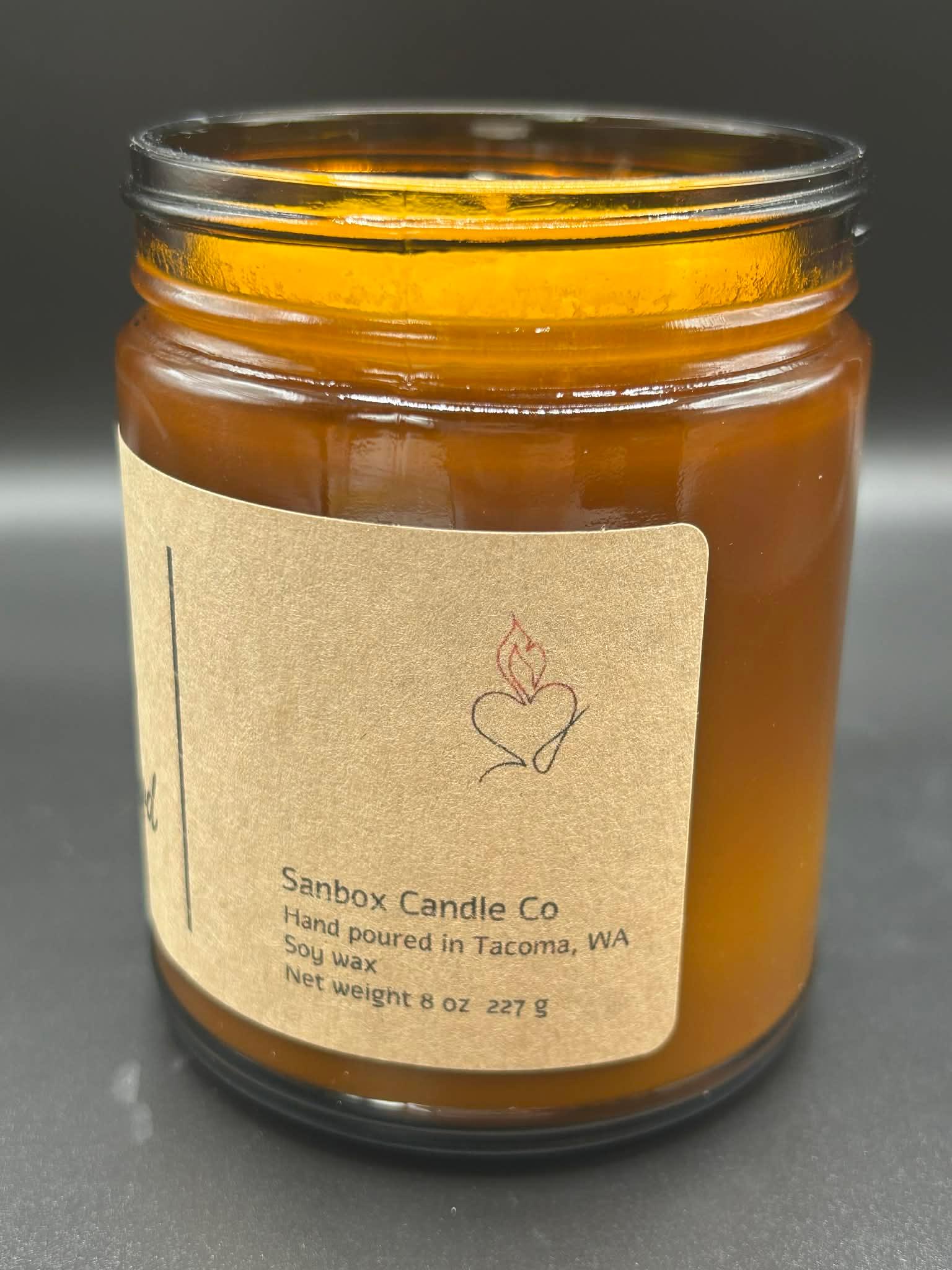 Amber glass soy wax candle with kraft label, hand poured, 8oz, on a dark background