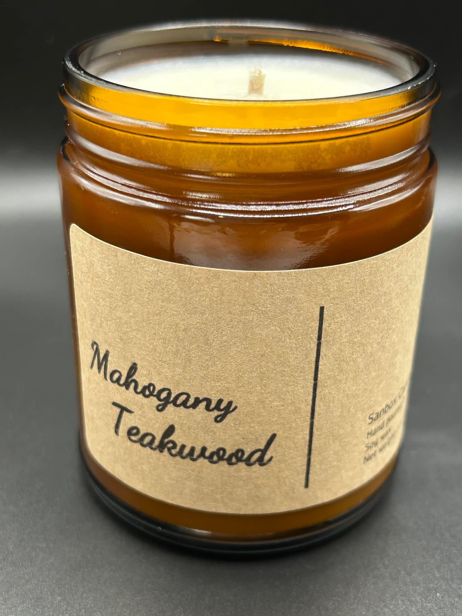 Mahogany Teakwood scented candle in amber glass jar with kraft label on black background