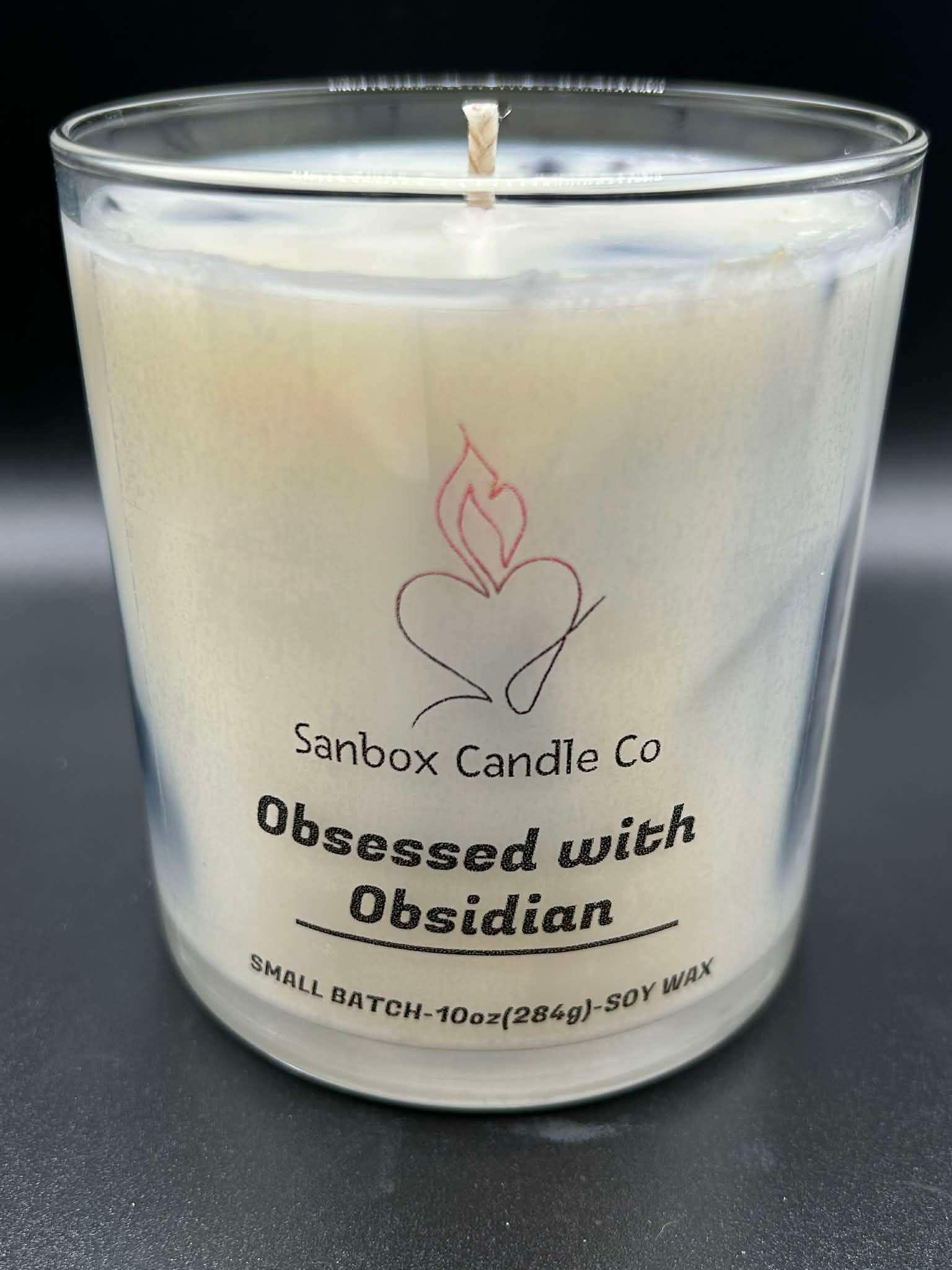 10oz soy wax candle labeled Obsessed with Obsidian in a clear glass jar on black background.