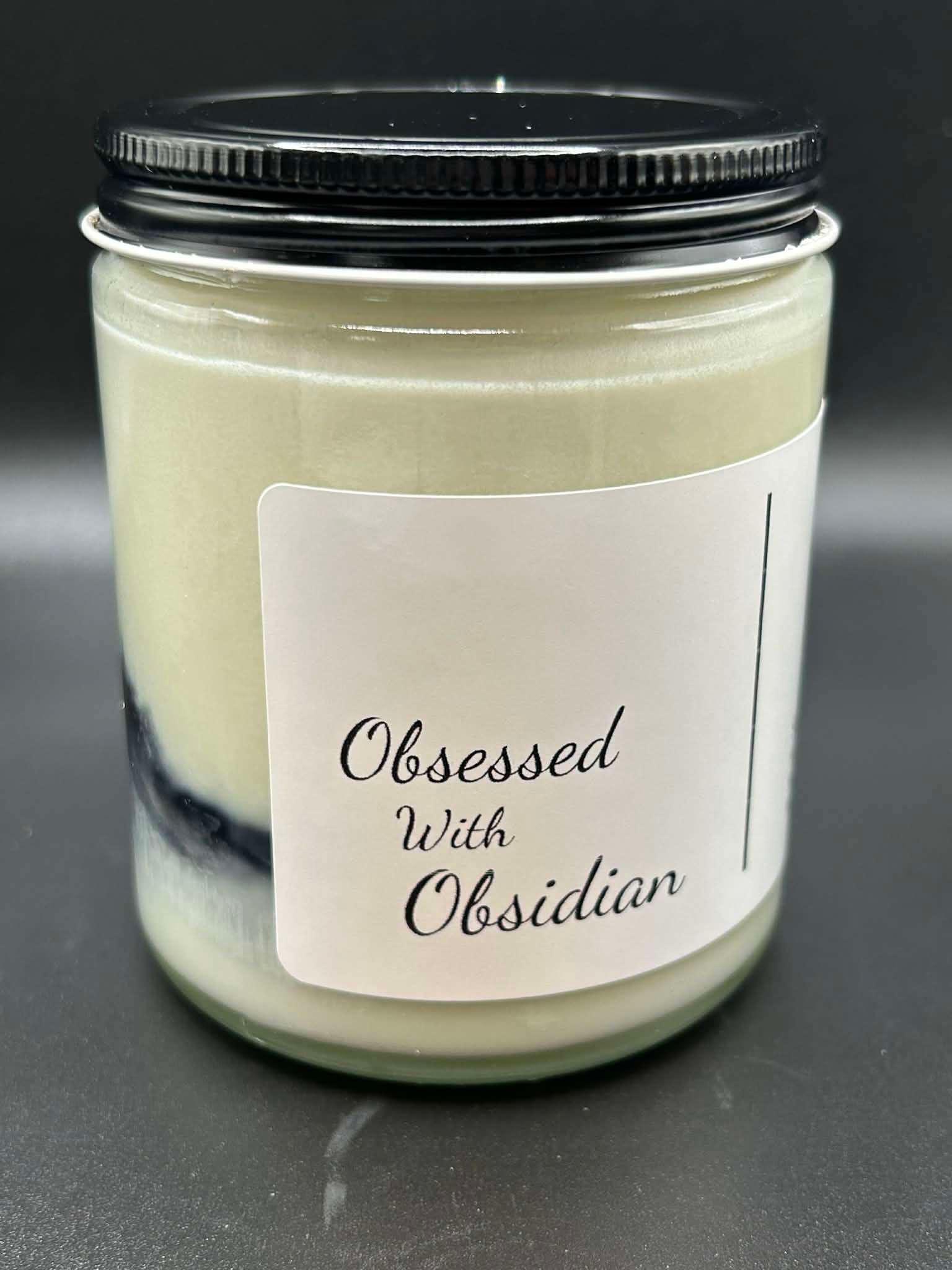 Hand-poured scented candle in glass jar with black lid labeled 'Obsessed With Obsidian'.