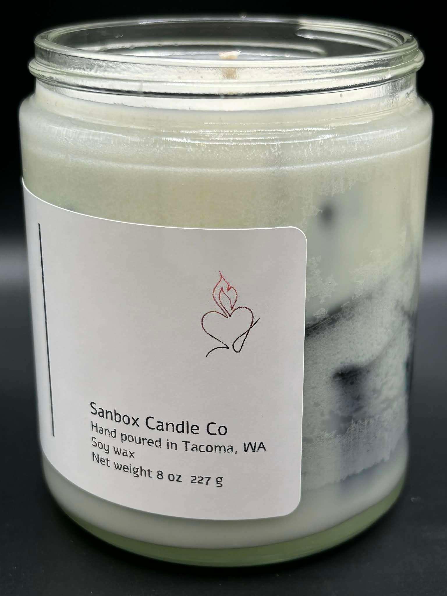 Hand-poured white soy wax candle in glass jar, minimalist label, 8oz, black background.
