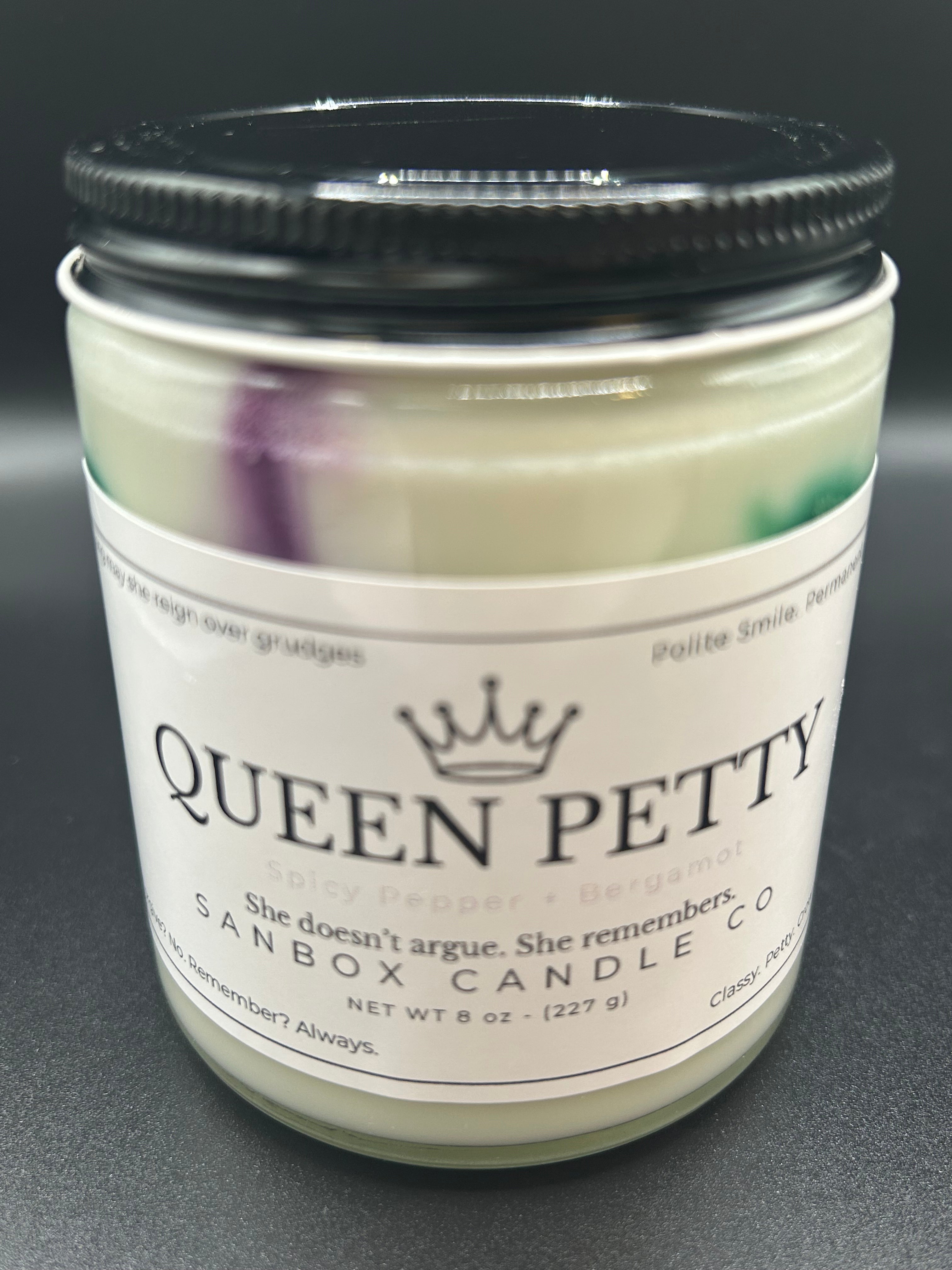 Queen Petty scented candle with black lid, labeled spicy pepper and bergamot, 8oz size