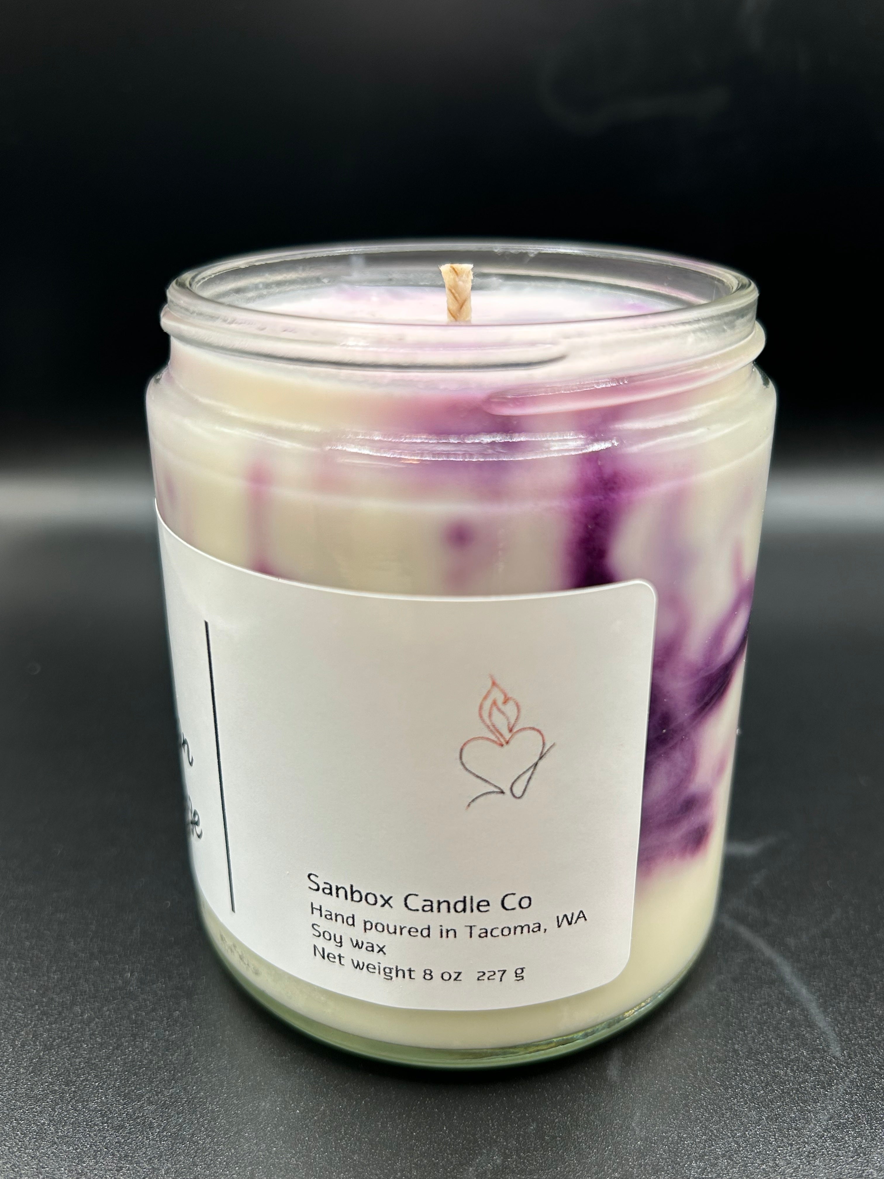 Hand-poured soy wax candle in glass jar with purple marbling and product label, 8oz