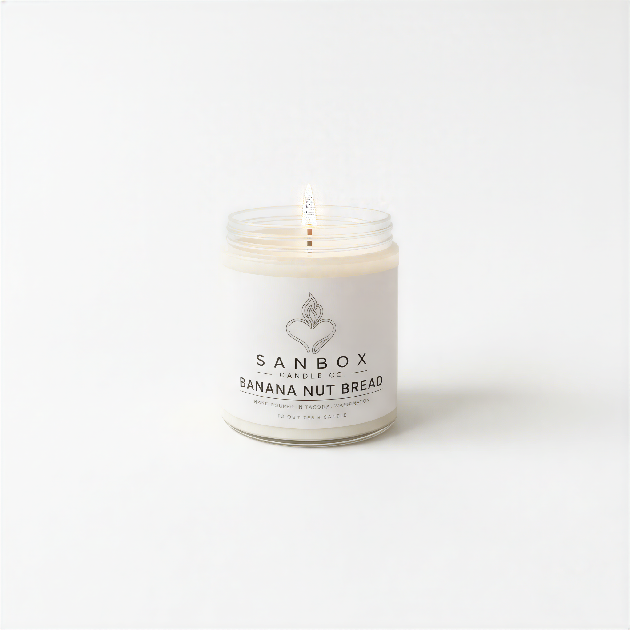 A white candle in a jar with a label that reads "SANBOX BANANA NUT BREAD".
