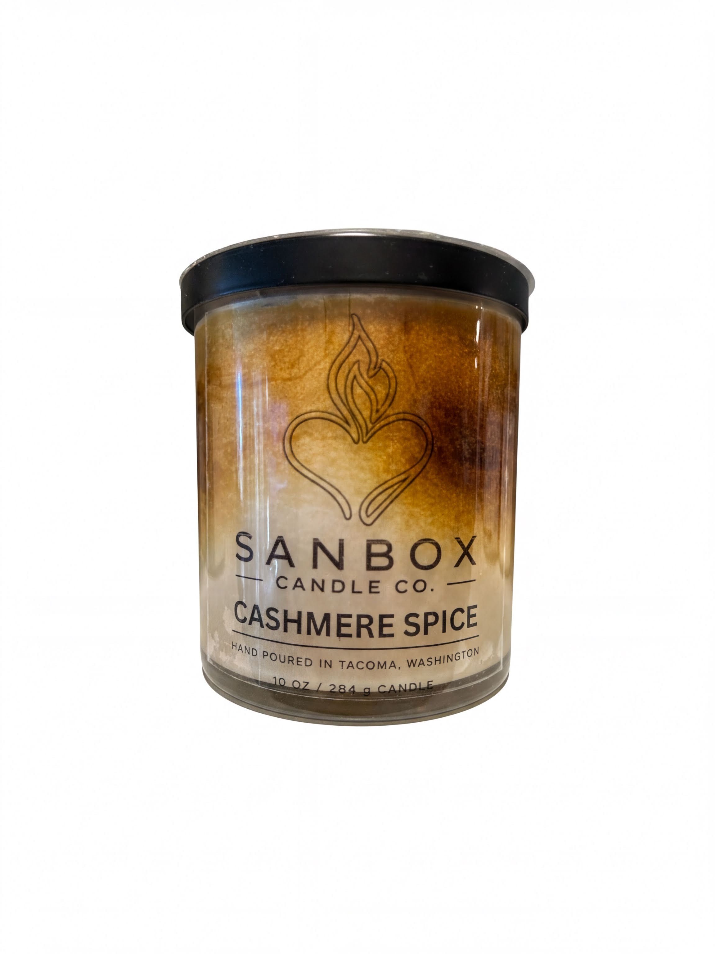 a cylindrical candle labeled "SANBOX CANDLE CO. CASHMERE SPICE" with a flame design. The candle is described as being hand poured in TACOMA, Washington and contains 10 OZ / 2.4 OZ of candle wax.