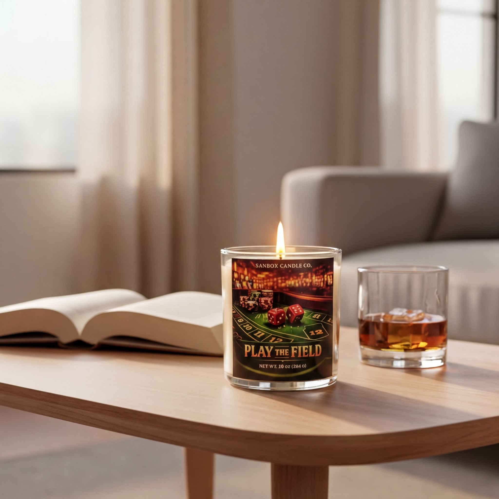 A lit candle on a wooden table, with an open book and a glass of whiskey nearby, creating a cozy and relaxing atmosphere.