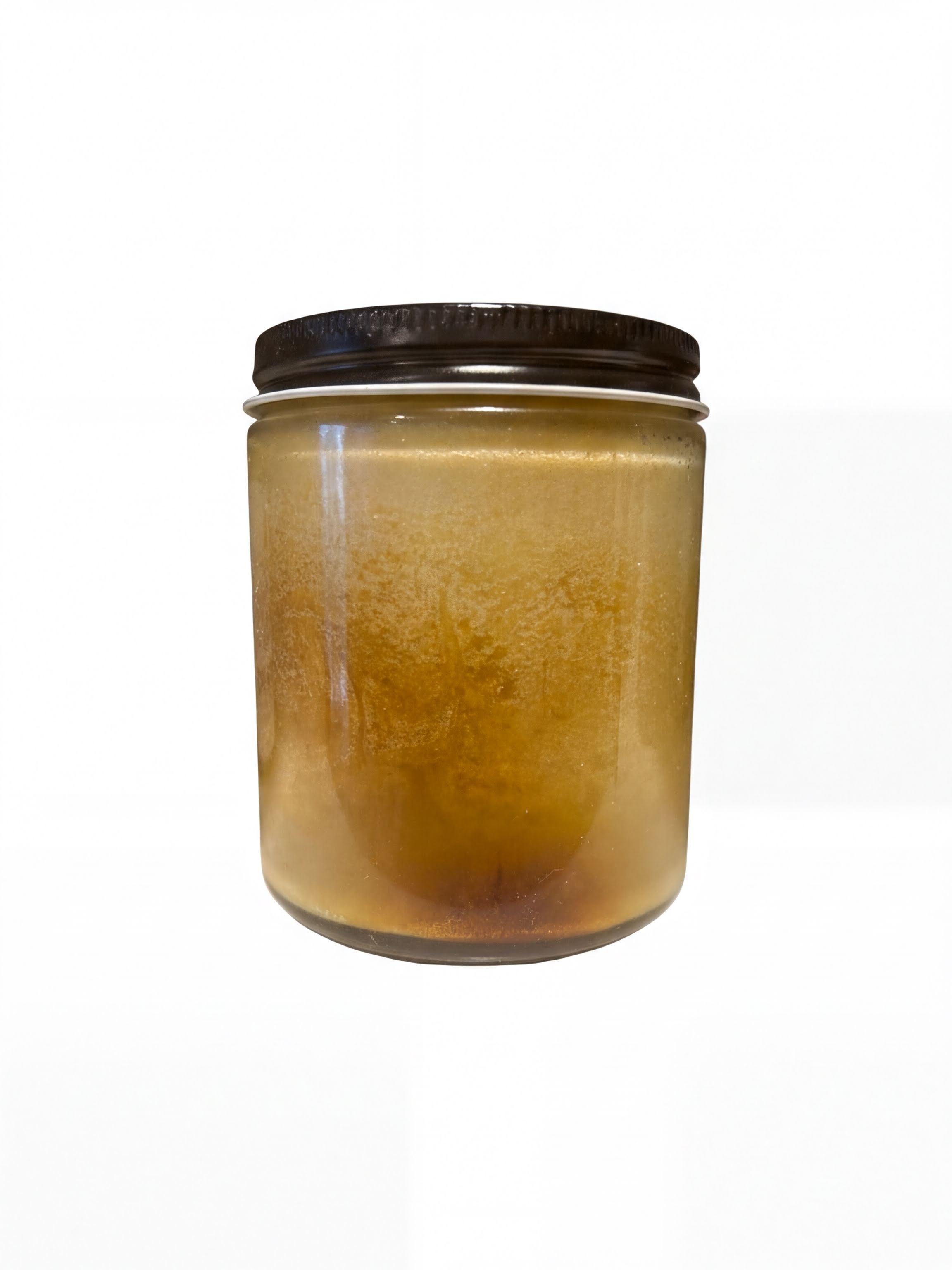 A glass jar containing a yellowish liquid, possibly honey or syrup, with a black lid.