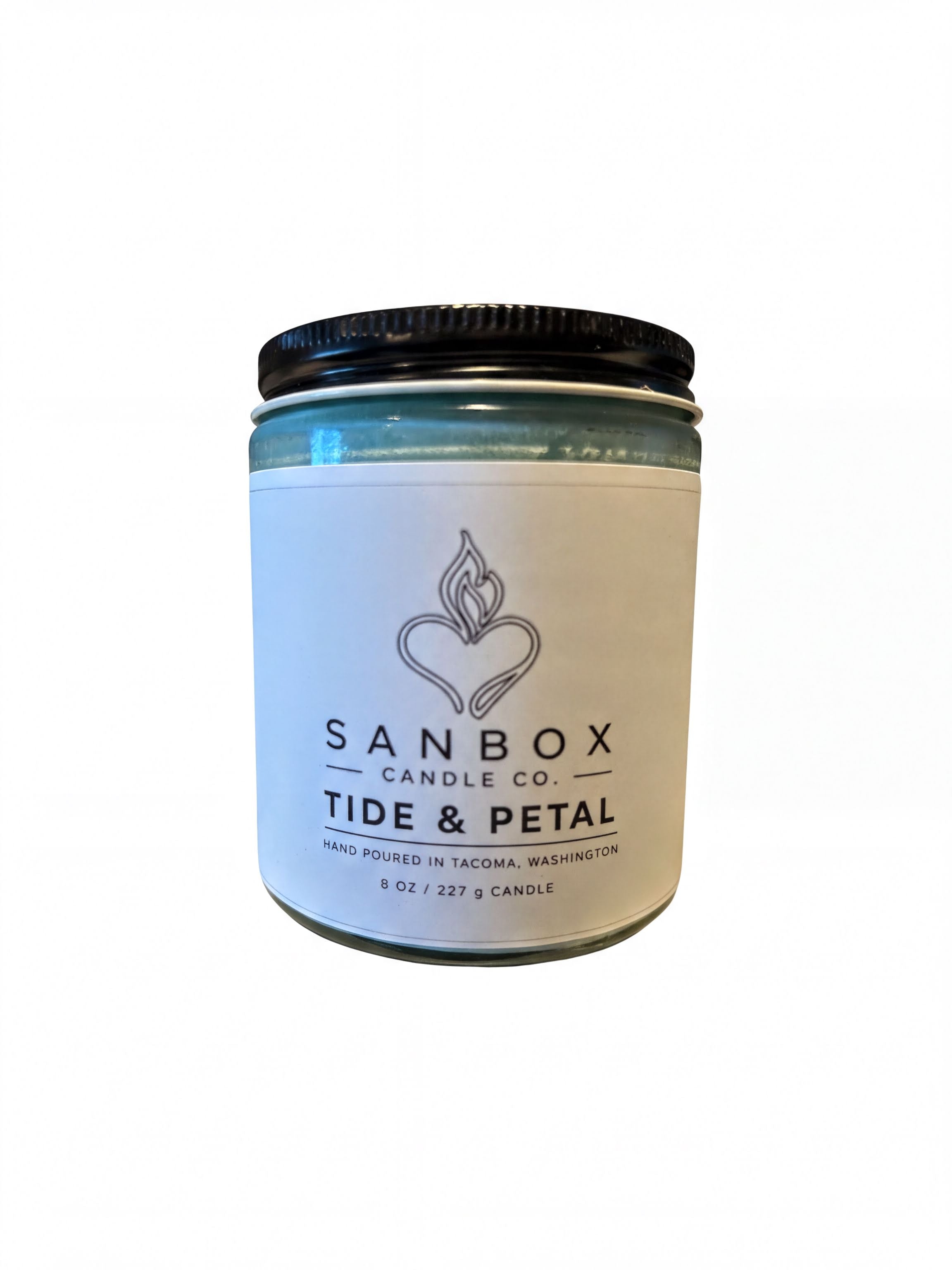 a candle jar with a label that reads "SANBOX CANDLE CO. TIDE & PETAL HAND Poured in TACOMA, WASHINGTON 8 OZ. 227 CANDLE".
