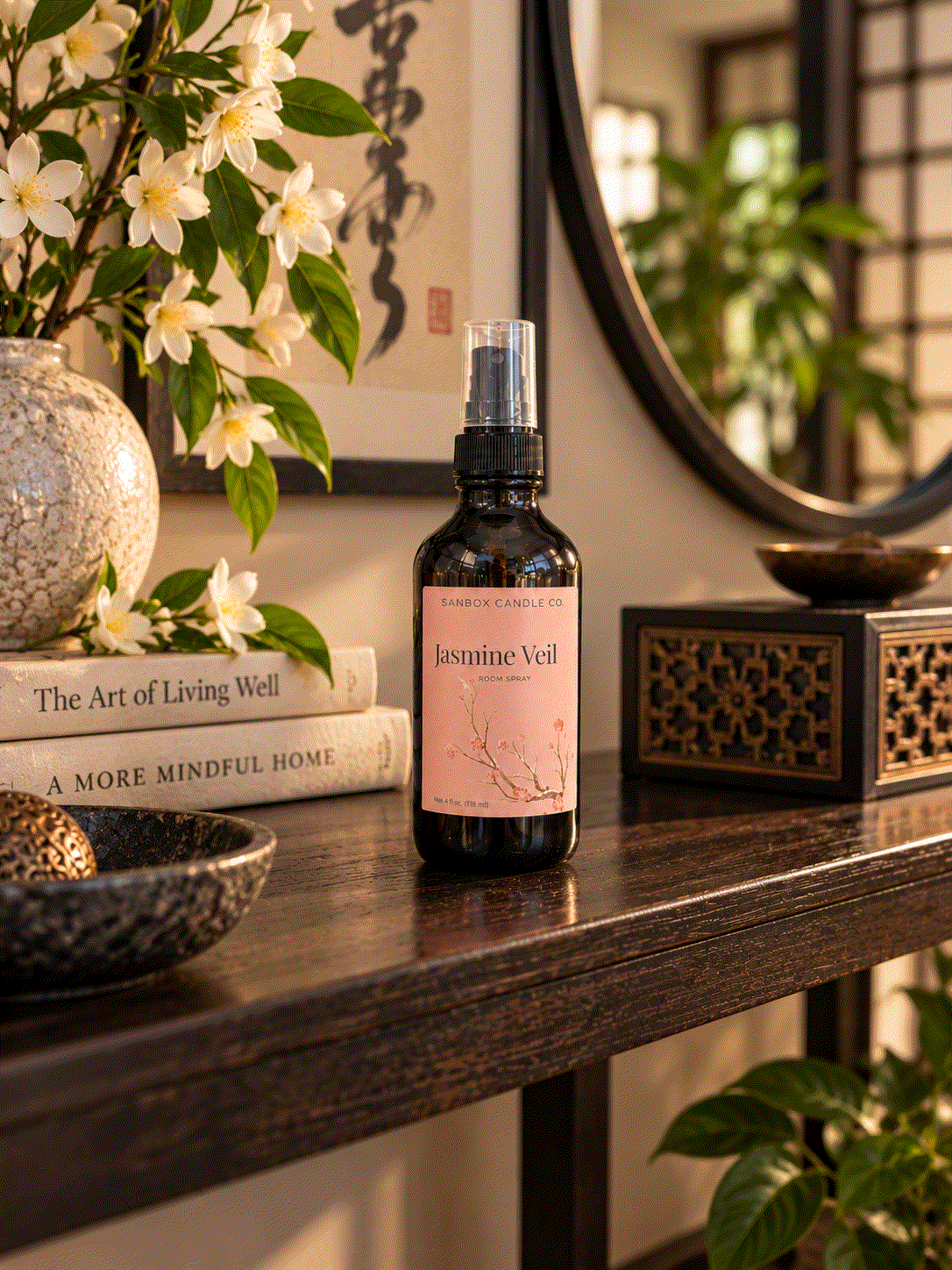 Jasmine Veil jasmine floral room spray in an amber bottle with a blush pink label, styled on a dark wood console beside jasmine blossoms and warm candlelight.