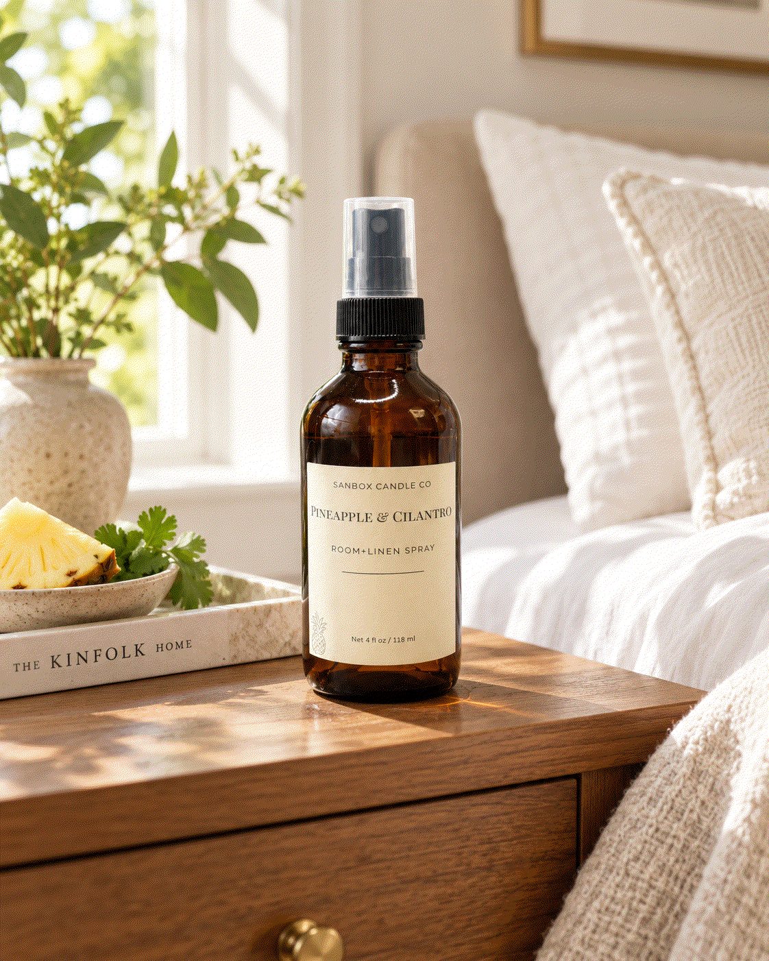 Pineapple & Cilantro room and linen spray in an amber glass bottle with black pump and clear cap, styled with fresh pineapple and cilantro in a kitchen.