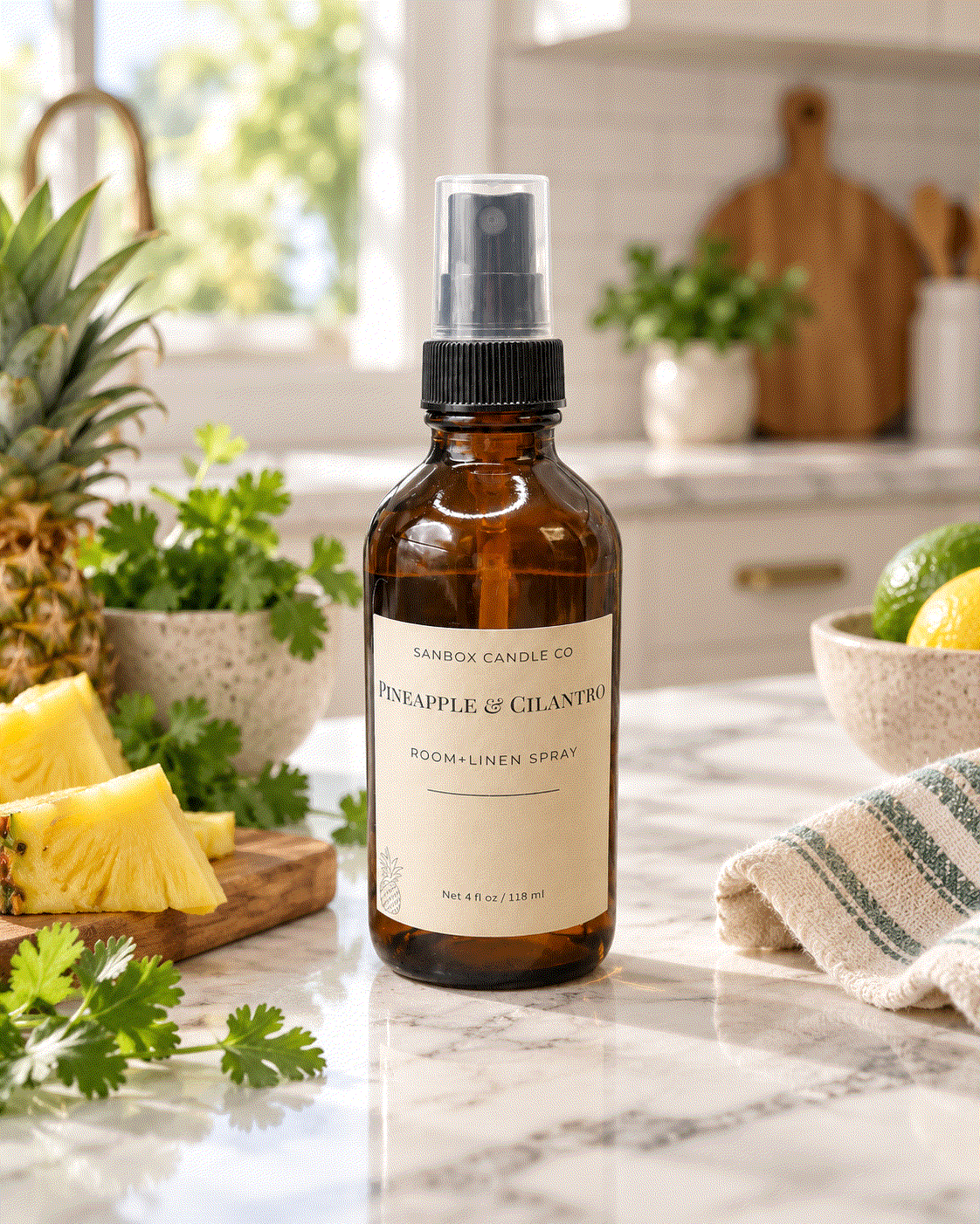 Pineapple & Cilantro room and linen spray in an amber glass bottle with black pump and clear cap, styled with fresh pineapple and cilantro in a kitchen.