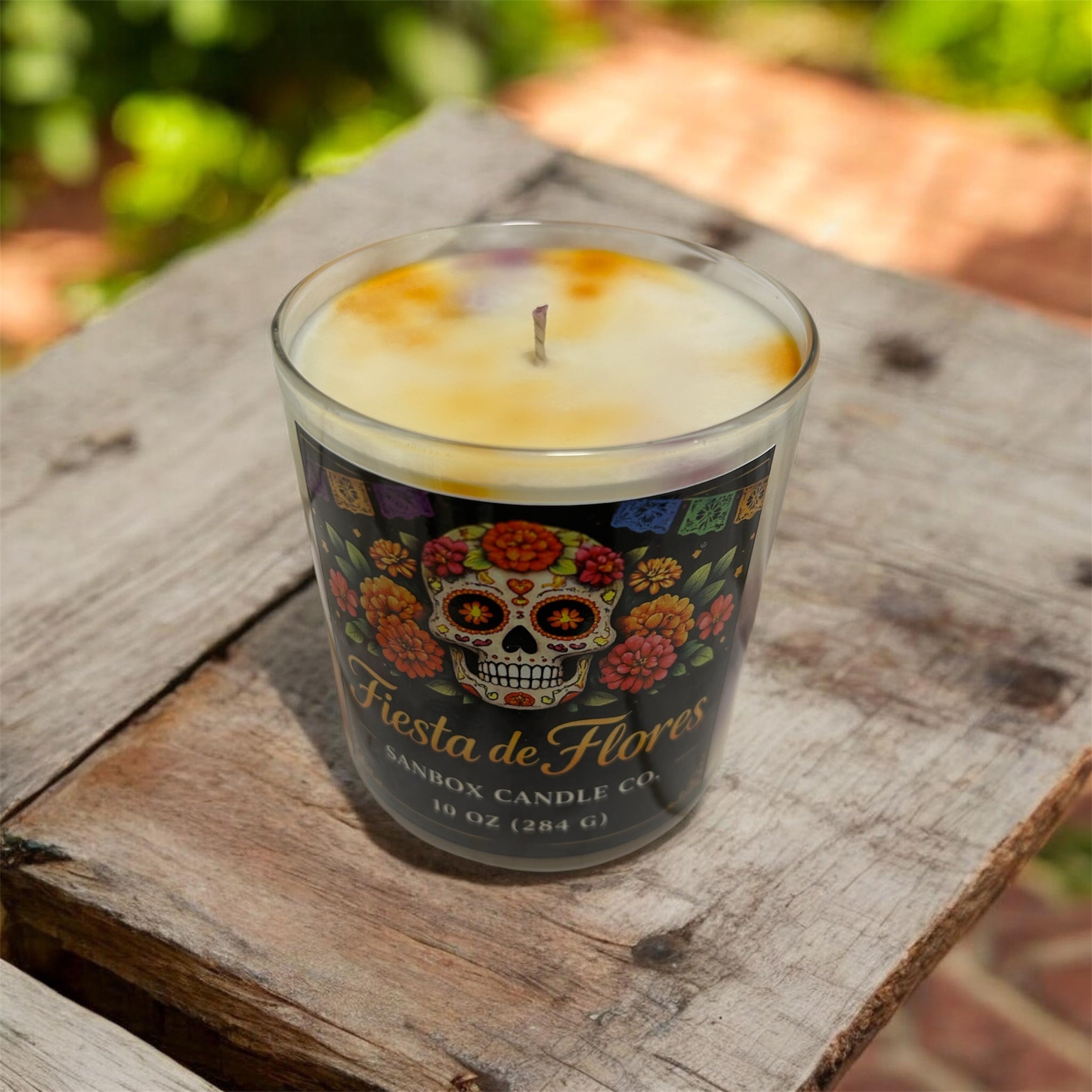 A glass candle holder with a candle in it, placed on a wooden surface.