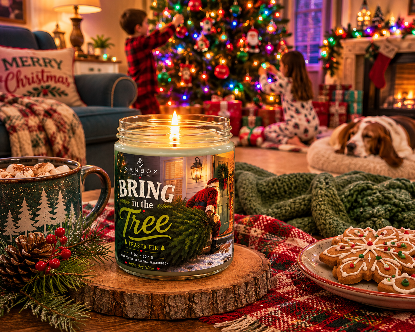 Lit Bring in The Tree Fraser Fir soy candle in a clear glass jar with soft green wax, displayed on a wood slice beside hot cocoa, holiday cookies, pinecones, and a decorated Christmas tree.